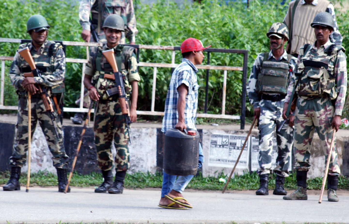 Indian soldiers of the CRPF Team and Assam police officers secure a street, as a Boy carries a Foul, during Garo National Council (GNC) Indefinite Bandh, Monday, In Paikan NH-51 and NH-37. (Pictures by Vishma Thapa)